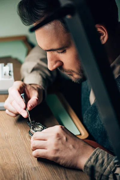 Side view of clockmaker repairing wristwatch at table — Stock Photo