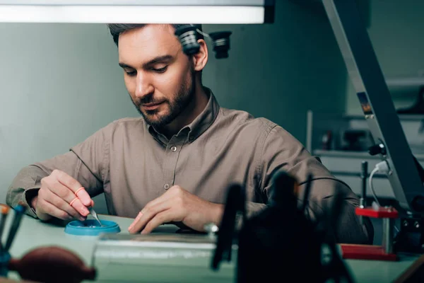 Selective focus of watchmaker working with watch parts in tool tray at table — Stock Photo