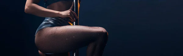 Panoramic shot of sexy stripper in panties standing near pylon isolated on blue — Stock Photo