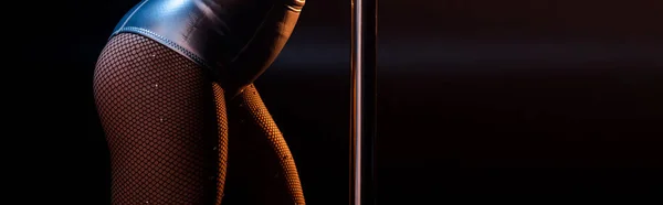 Plan panoramique de femme sexy debout près de pylône sur noir — Photo de stock