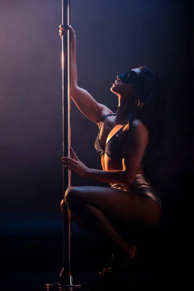 Side view of blindfolded stripper in underwear dancing striptease near pylon on black — Stock Photo