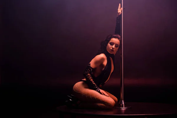 Beautiful stripper dancing near pylon on black with copy space — Stock Photo