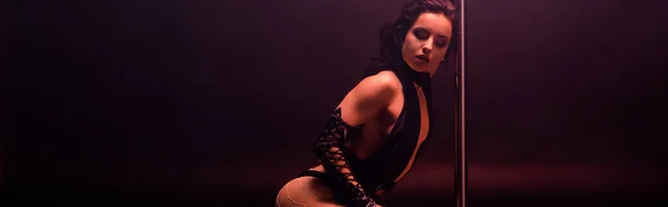 Tiro panorâmico de bela stripper dançando perto de pilão em preto — Fotografia de Stock