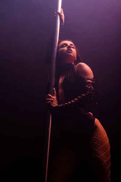 Low angle view of sexy stripper pole dancing on black — Stock Photo
