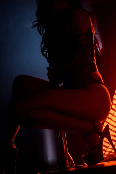 Silhouette de strip-teaseuse sexy pole danse sur bleu avec éclairage rouge — Photo de stock