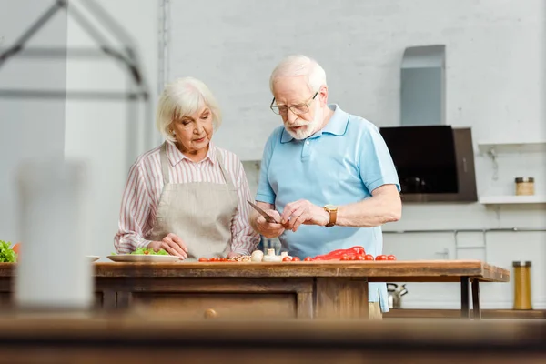Focus selettivo della coppia anziana che cucina insieme sul tavolo della cucina — Foto stock
