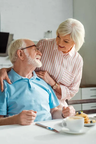 Selektiver Fokus des Seniorenpaares, das sich beim Frühstück in der Küche anlächelt — Stockfoto