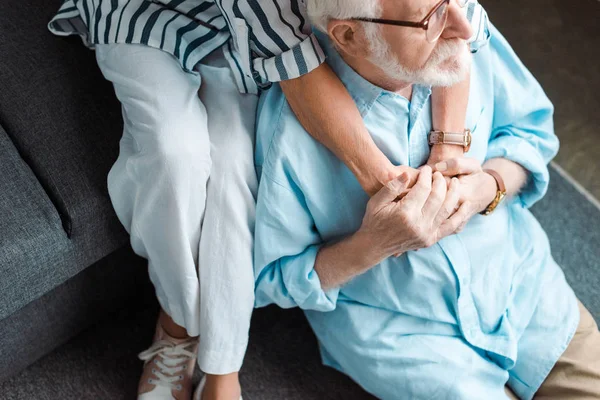 Overhead view of senior man holding hands of wife while sitting on floor at home — Stock Photo