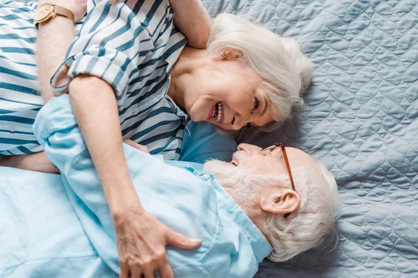 Вид сверху пожилой пары, улыбающейся друг другу на кровати — стоковое фото