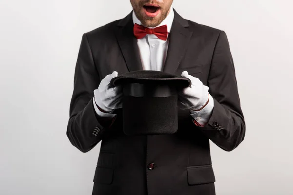 Vista recortada del sombrero de mano de mago sorprendido, aislado en gris - foto de stock