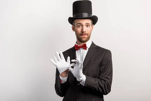 Schöner Zauberer zieht Handschuhe aus, isoliert auf grau — Stockfoto