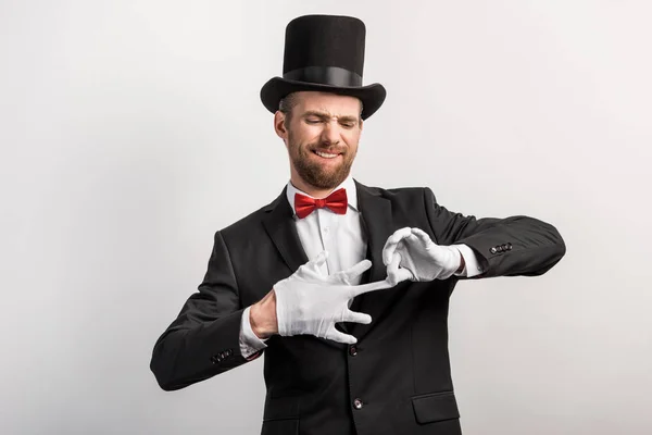 Emotionaler Zauberer zieht Handschuhe aus, isoliert auf grau — Stockfoto