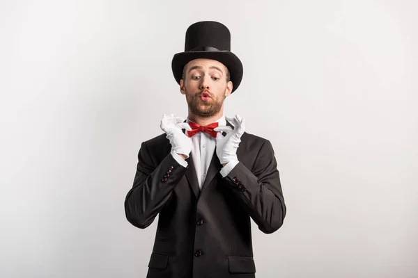 Emotional magician adjusting red bow tie, isolated on grey — Stock Photo