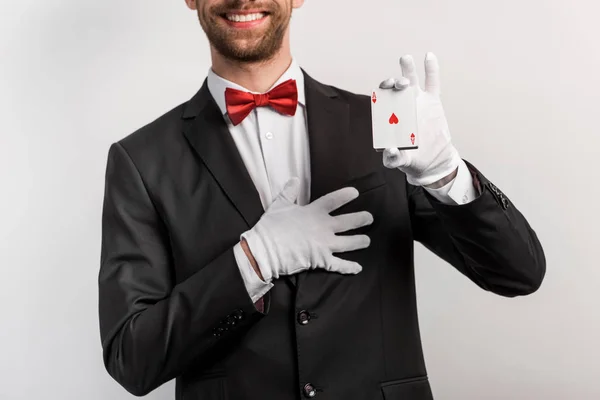 Vista recortada del mago sonriente sosteniendo cartas, aislado en gris - foto de stock