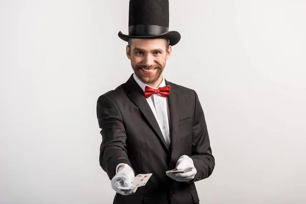 Cheerful magician holding playing cards, isolated on grey — Stock Photo