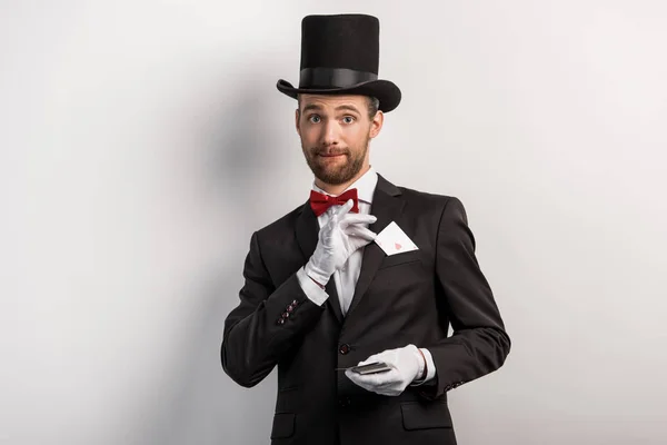 Emotional magician holding playing cards, on grey — Stock Photo