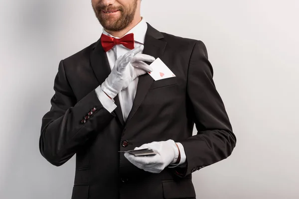 Cropped view of magician holding playing cards, isolated on grey — Stock Photo