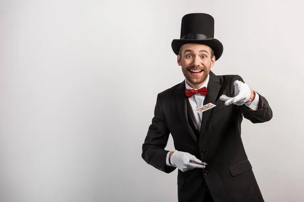 Happy magician holding playing cards, isolated on grey — Stock Photo