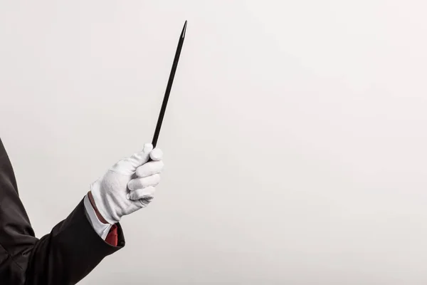 Partial view of magician in glove holding wand, isolated on grey — Stock Photo