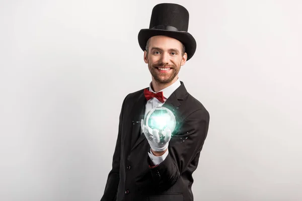 Professional magician holding blue magic ball, isolated on grey — Stock Photo