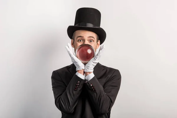 Professional magician holding magic ball, isolated on grey — Stock Photo