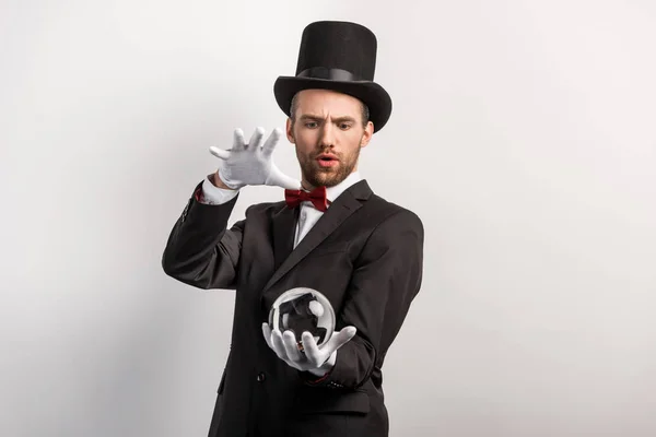 Focused professional magician holding magic ball, isolated on grey — Stock Photo