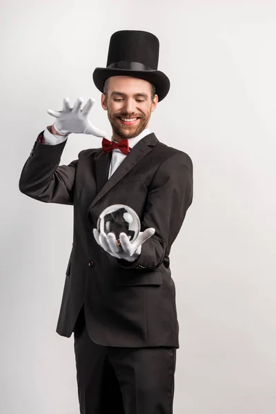 Felice mago professionista in possesso di palla magica, isolato su grigio — Foto stock