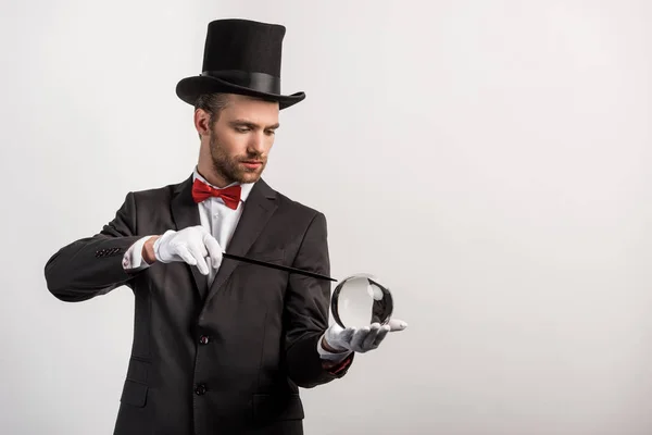 Professional magician holding wand and magic ball, isolated on grey — Stock Photo