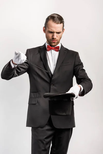 Confused magician in suit making trick hat and wand, isolated on grey — Stock Photo