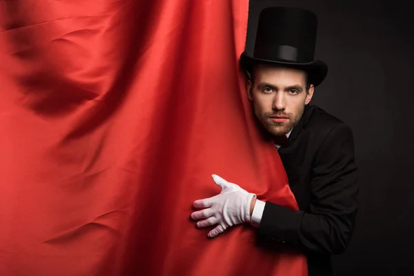 Mago guapo en traje y sombrero en circo con cortinas rojas - foto de stock