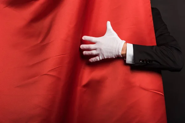 Vista recortada de mago en guante tocando cortinas rojas - foto de stock