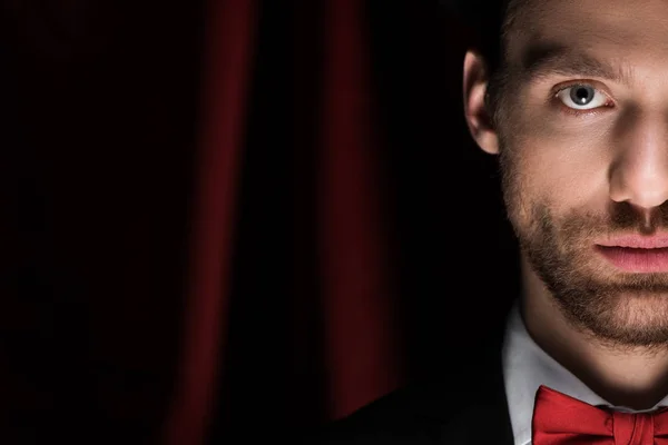 Handsome magician in black suit in circus with red curtains — Stock Photo