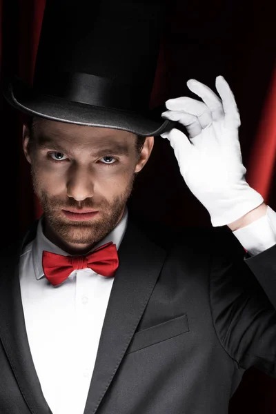 Caballero de traje y sombrero de circo con cortinas rojas - foto de stock