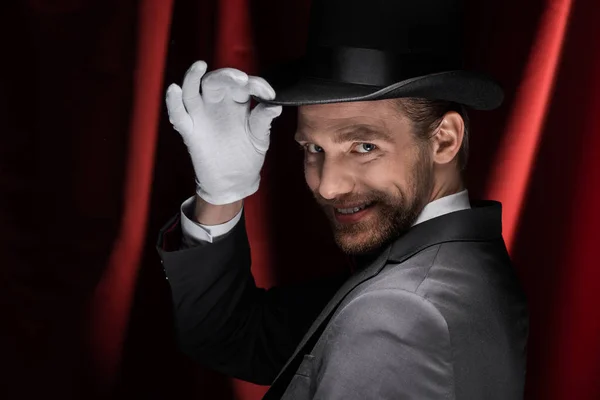 Scary smiling magician in circus with red curtains — Stock Photo