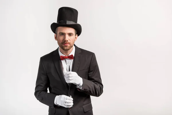 Handsome magician in suit and hat holding wand, isolated on grey — Stock Photo