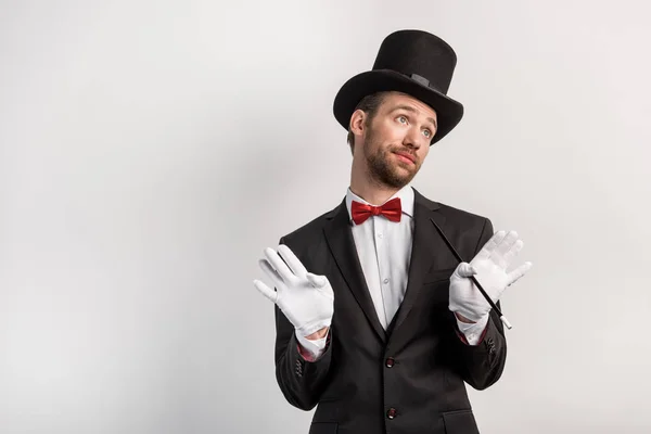 Magicien émotionnel avec geste hausseur tenant la baguette, sur gris — Photo de stock