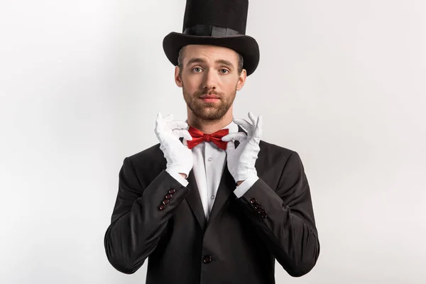 Confident magician adjusting bow tie, isolated on grey — Stock Photo