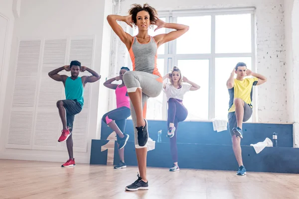 Enfoque selectivo del entrenador afroamericano haciendo ejercicio con bailarines multiétnicos de zumba en estudio de danza - foto de stock