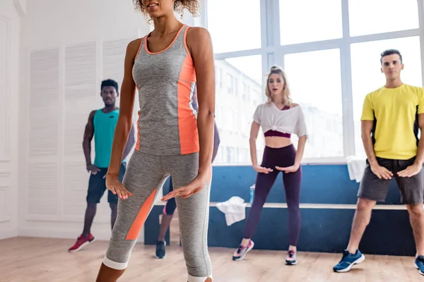 Focus selettivo del trainer afroamericano che mostra movimenti a ballerini di zumba multietnici in studio di danza — Foto stock