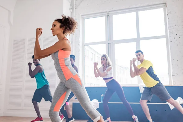 Enfoque selectivo del entrenador afroamericano practicando movimientos con bailarines multiétnicos de zumba en estudio de danza - foto de stock