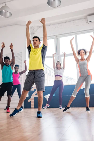 Focus selettivo di trainer e ballerini multiculturali che eseguono zumba in studio di danza — Foto stock