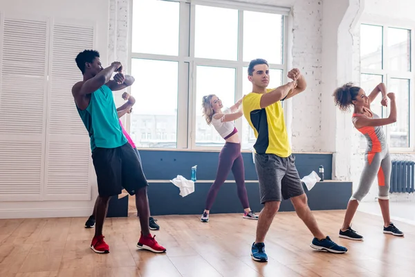 Jóvenes bailarines multiculturales de zumba ejercitando movimientos en estudio de danza - foto de stock