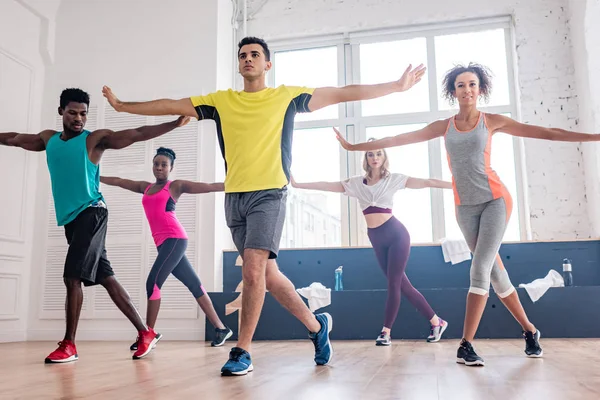 Low angle view of handsome trainer performing zumba with multicultural dancers in studio — Stock Photo