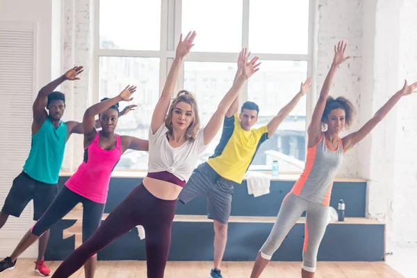 Selective focus of multicultural zumba dancers with hands in air training together in dance studio — Stock Photo