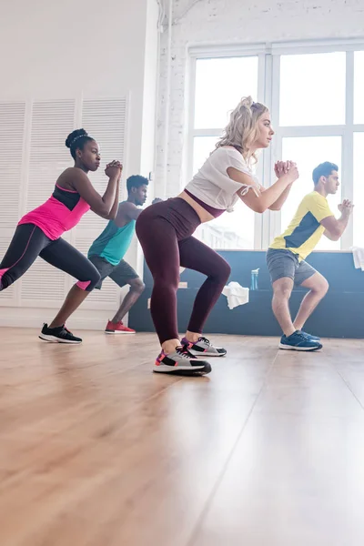 Vue en angle bas de danseurs de zumba multiethniques s'étirant tout en s'entraînant dans un studio de danse — Photo de stock