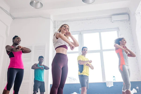 Vista a basso angolo di ballerini multiculturali che esercitano zumba insieme in studio di danza — Foto stock