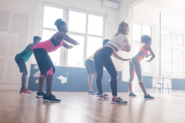 Seitenansicht junger multikultureller Tänzer, die Zumba-Bewegungen im Tanzstudio trainieren — Stockfoto