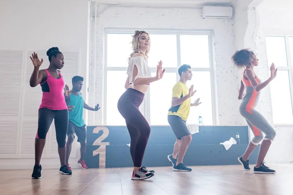 Vista lateral de dançarinos multiétnicos tocando zumba no estúdio de dança — Fotografia de Stock