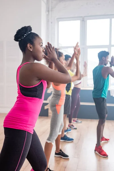 Foco seletivo de dançarinos multiétnicos realizando zumba com treinador afro-americano em estúdio — Fotografia de Stock