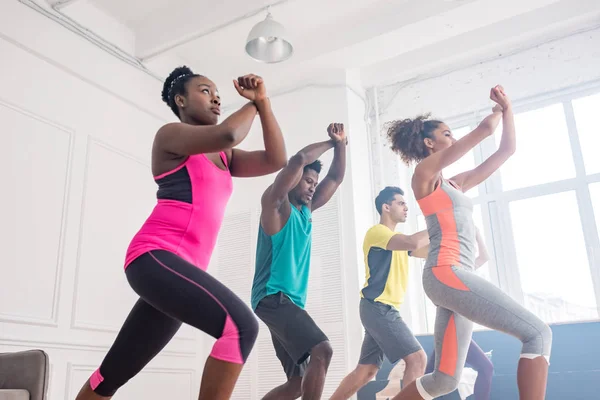 Vue en angle bas de l'apprentissage des formateurs afro-américains avec des mouvements de danseurs multiculturels de zumba dans un studio de danse — Photo de stock